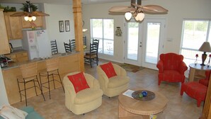 A spacious living area with a kitchen, dining area, and a red armchair.