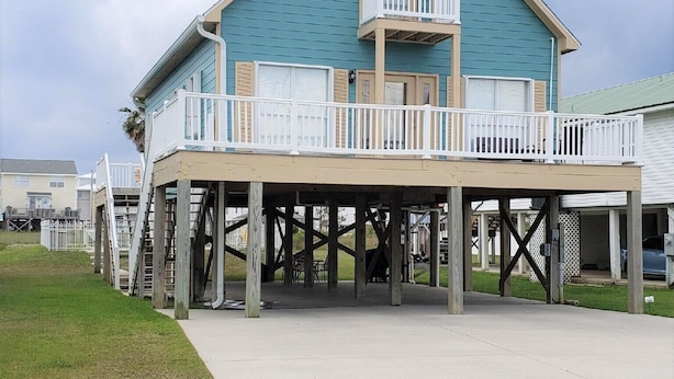 A two-story building with a balcony on the upper floor, supported by wooden stilts.