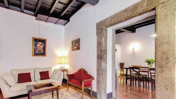 A living room with a sofa, armchair, lamp, and a dining area with chairs and a table. - Campo Dei Fiori Stunning And Quiet (Rome)