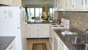 A modern kitchen with white cabinets, granite countertops, a stove, and a sink.
