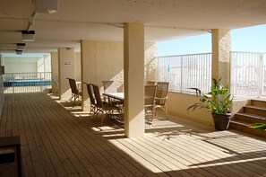 A covered outdoor area with wooden flooring, chairs, and a table. - Low Density Gulf Front Condo | Sleeps 6 (Gulf Shores)