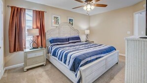 A bedroom with a bed, nightstands, a ceiling fan, and a window with curtains.