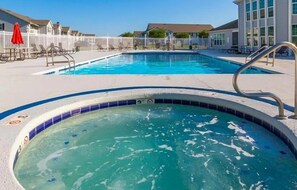 A swimming pool area with a hot tub, lounge chairs, and a fence. - 2BR Gulf Shores Condo | Central Location + Short Drive to Beach (Gulf Shores)