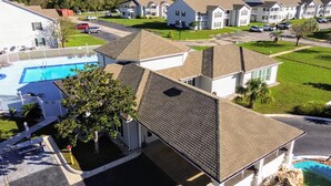 A residential building with a swimming pool, a covered patio, and a well-maintained lawn. - 2BR Gulf Shores Condo | Central Location + Short Drive to Beach (Gulf Shores)