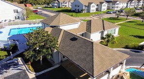 A residential building with a swimming pool, a covered patio, and a well-maintained lawn.