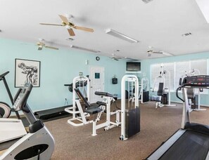 A gym with exercise equipment, ceiling fans, and a treadmill.
