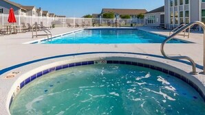 A swimming pool area with a hot tub, lounge chairs, and a fence. - 2BR Gulf Shores Condo | Central Location + Short Drive to Beach (Gulf Shores)