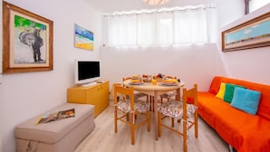 Un espacio habitable compacto con una mesa de comedor, sillas, un sofá, un televisor y obras de arte en las paredes.