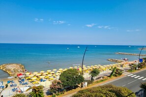 A beachside view with umbrellas, lounge chairs, and a clear blue sky. - Laigueglia Beach (Laigueglia)