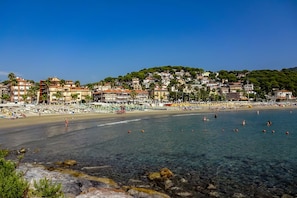 A coastal town with a beach, clear waters, and buildings with balconies.