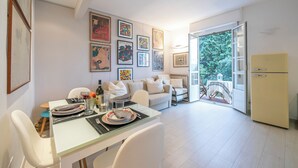 A modern kitchen with a dining area, white furniture, and a view of greenery through the open door. - La Casa Al Sole Sea View 400mt From Sea (Andora)