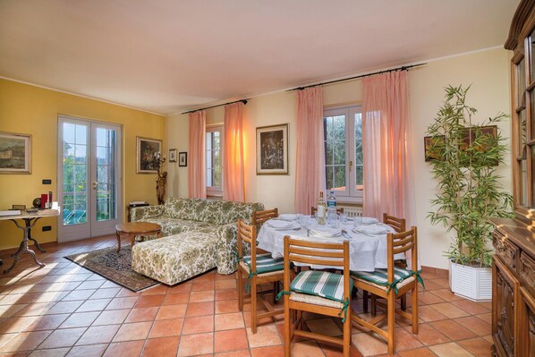 A dining area with a table set for four, a sofa, and a potted plant. - La Casetta Sull'Albero child friendly (Albenga)