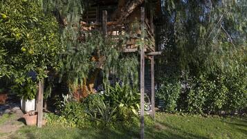 Une structure de pergola en bois, entourée d’une végétation luxuriante et d’un jardin bien entretenu.