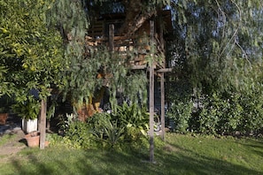 Una estructura de pérgola de madera rodeada de exuberante follaje y plantas en macetas.