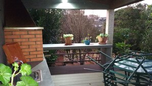 A covered patio area with a brick wall, a metal table, and potted plants.