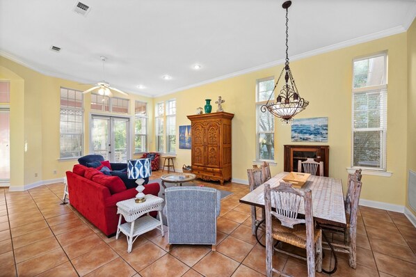 A spacious living room with a red sofa, a patterned armchair, a wooden cabinet, and a dining table with chairs.