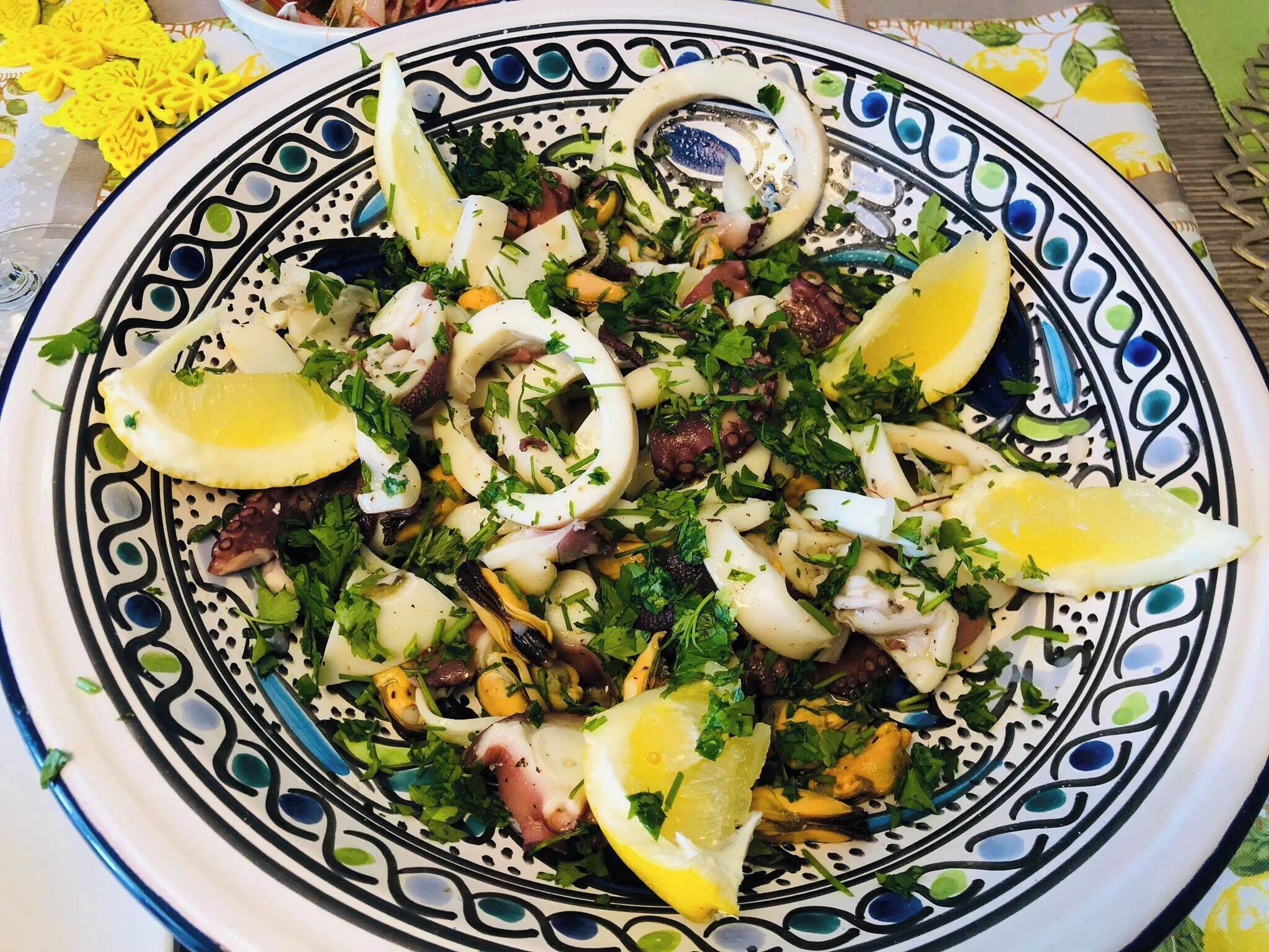 Un piatto di insalata di pesce con fette di limone e prezzemolo.