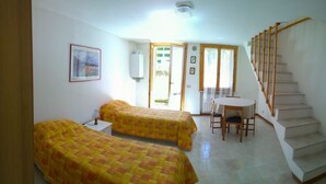 A room with two beds, a small table, and a staircase.
