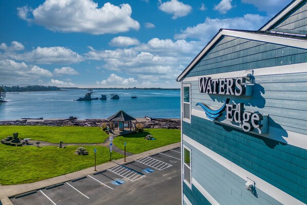 A hotel named 'Waters Edge' with a view of the ocean and a gazebo in the parking lot.