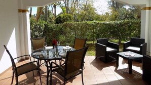 An outdoor patio with a round table and chairs, surrounded by wicker furniture.