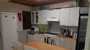 Una cocina compacta con gabinetes blancos, microondas, tostadora y refrigerador.