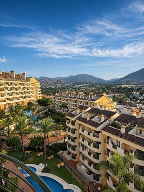 Un hôtel de grande hauteur doté de nombreux balcons, d’une piscine et offrant une vue sur un paysage montagneux.