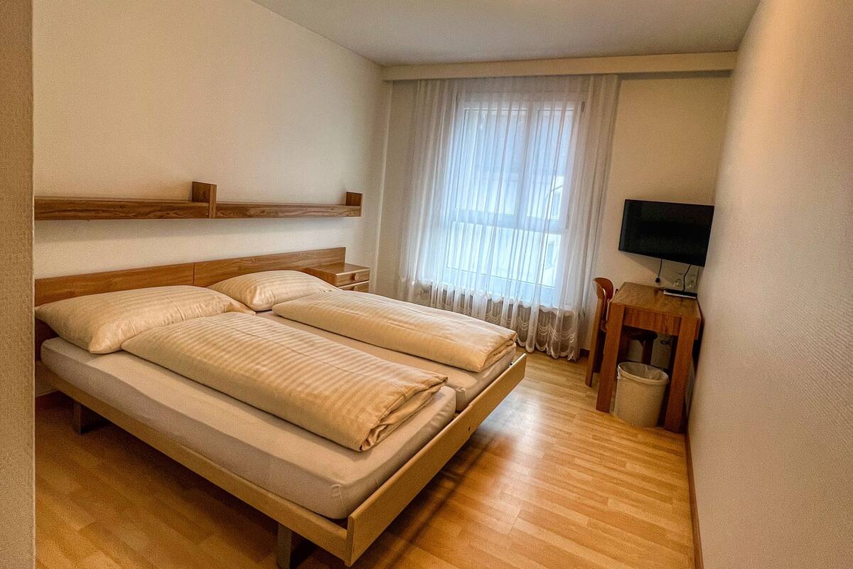 A hotel room with a bed, a television, and a small table.