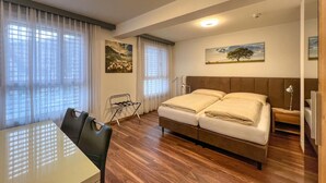 A hotel room with a bed, a desk, and a chair. There are two paintings on the walls. - Hotel Hecht (Rheineck)