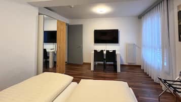 Quarto de hotel com duas camas, televisão, escrivaninha e cadeira.