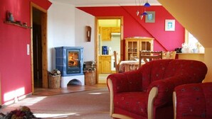 A cozy living room with a red sofa, a blue fireplace, and a dining area with wooden furniture.