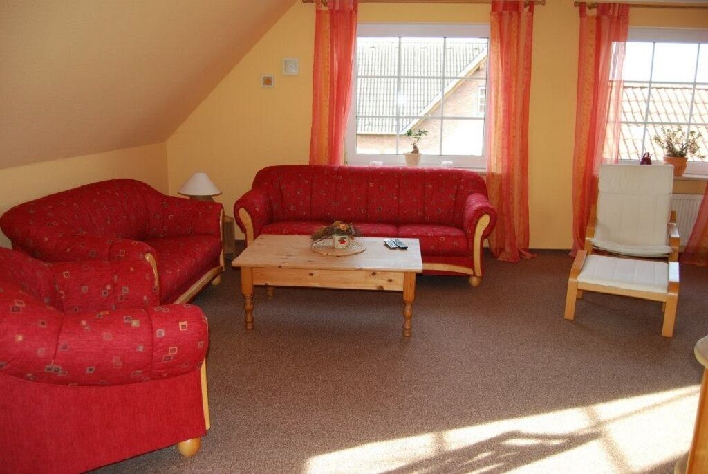 A cozy living room with a red sofa set, a wooden coffee table, and a white armchair.
