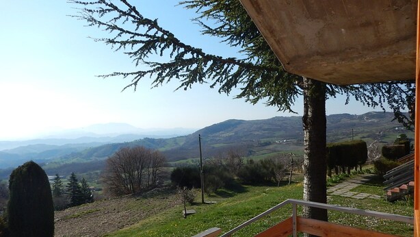 A wooden bench overlooking a scenic landscape with rolling hills and a clear sky. - Residence Le Terrazze sul Montefeltro (Carpegna)