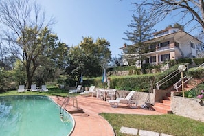 Une piscine avec des chaises longues et un escalier menant à une maison.
