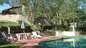 A swimming pool surrounded by a brick patio with lounge chairs and a table. - Villa with 2 spacious apartments for 2 x 7 people and swimming pool near Pisa and the sea (Fauglia)