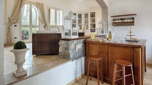 A kitchen with a bar area, stone accents, and a wine tasting sign. - Luxury Villa In Sorrento Coast Strategic Location (Massa Lubrense)