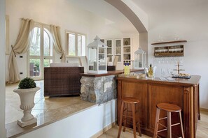 A kitchen with a bar area, stone accents, and a wine tasting sign. - Luxury Villa In Sorrento Coast Strategic Location (Massa Lubrense)