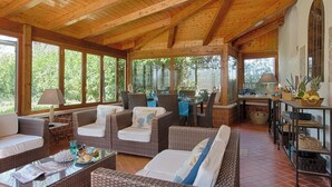 A covered outdoor seating area with wicker furniture, a dining table, and a kitchen area with a lamp and basket. - Luxury Villa In Sorrento Coast Strategic Location (Massa Lubrense)