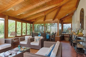 A covered outdoor seating area with wicker furniture, a dining table, and a kitchen area with a lamp and basket. - Luxury Villa In Sorrento Coast Strategic Location (Massa Lubrense)