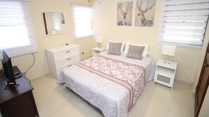 Un dormitorio con una cama, mesitas de noche, un escritorio y un ventilador de techo.