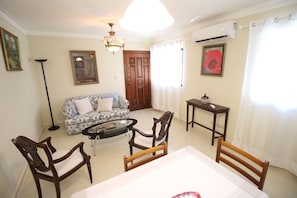 A living room with a sofa, chairs, a coffee table, and a dining table.