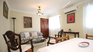Una habitación con una mesa de comedor, sillas, un sofá, una lámpara de pie y un aplique de techo.