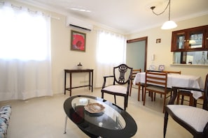 A dining area with a glass-top table, wooden chairs, and a cabinet with glassware.