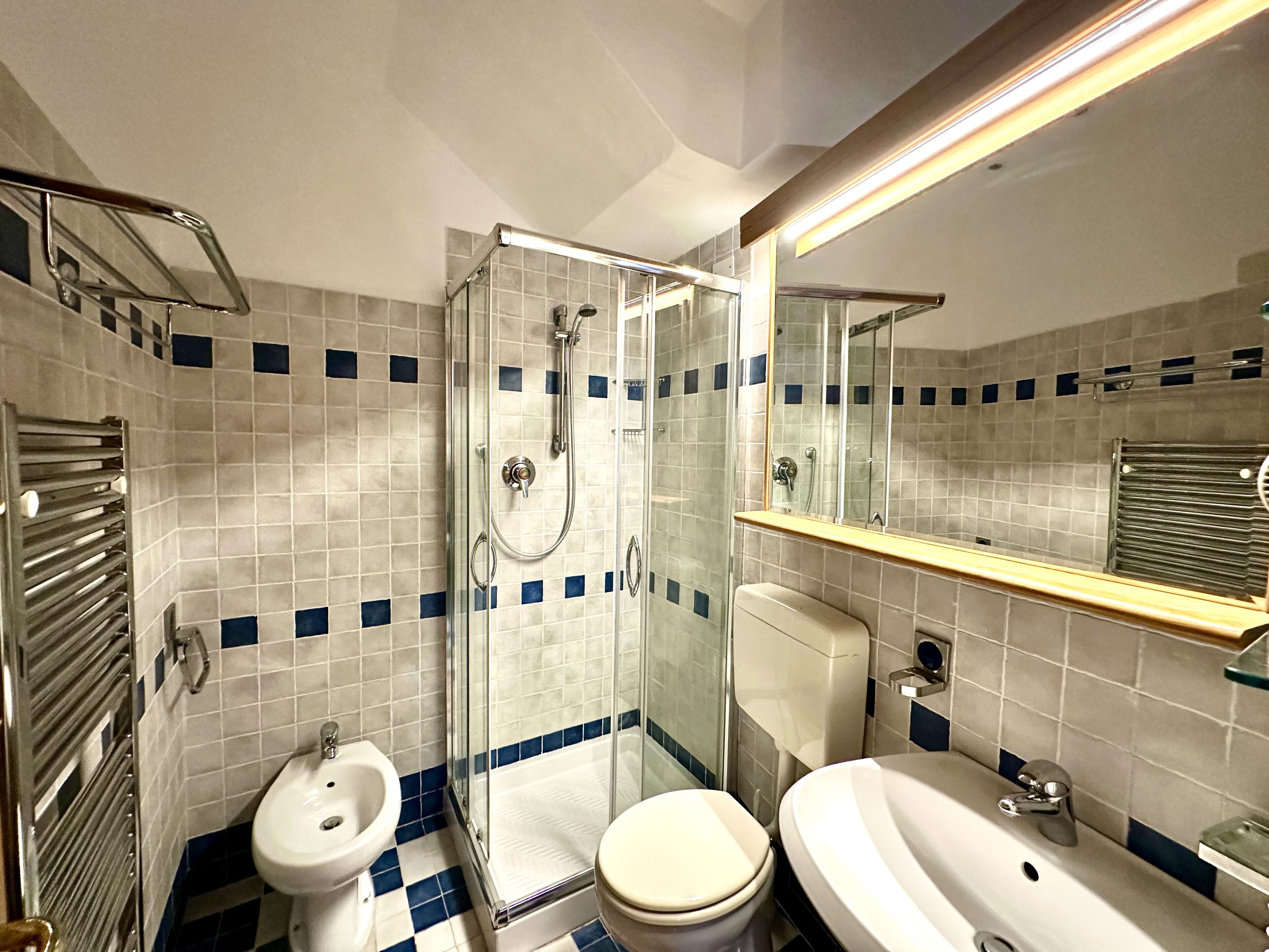 A bathroom with a glass-enclosed shower, a bidet, a toilet, and a sink.