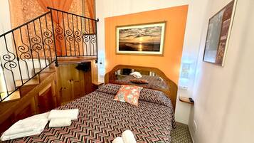 Una habitación de hotel con una cama, una escalera de madera, un cuadro en la pared y un espejo.