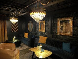 A dimly lit lounge area with dark sofas, a wooden coffee table, and ornate chandeliers. - POOL - Speakeasy Club ON SITE  - NASHVILLE Broadway fun - free parking (Nashville)