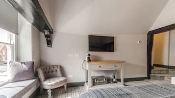 A bedroom with a bed, a chair, a desk, and a television.