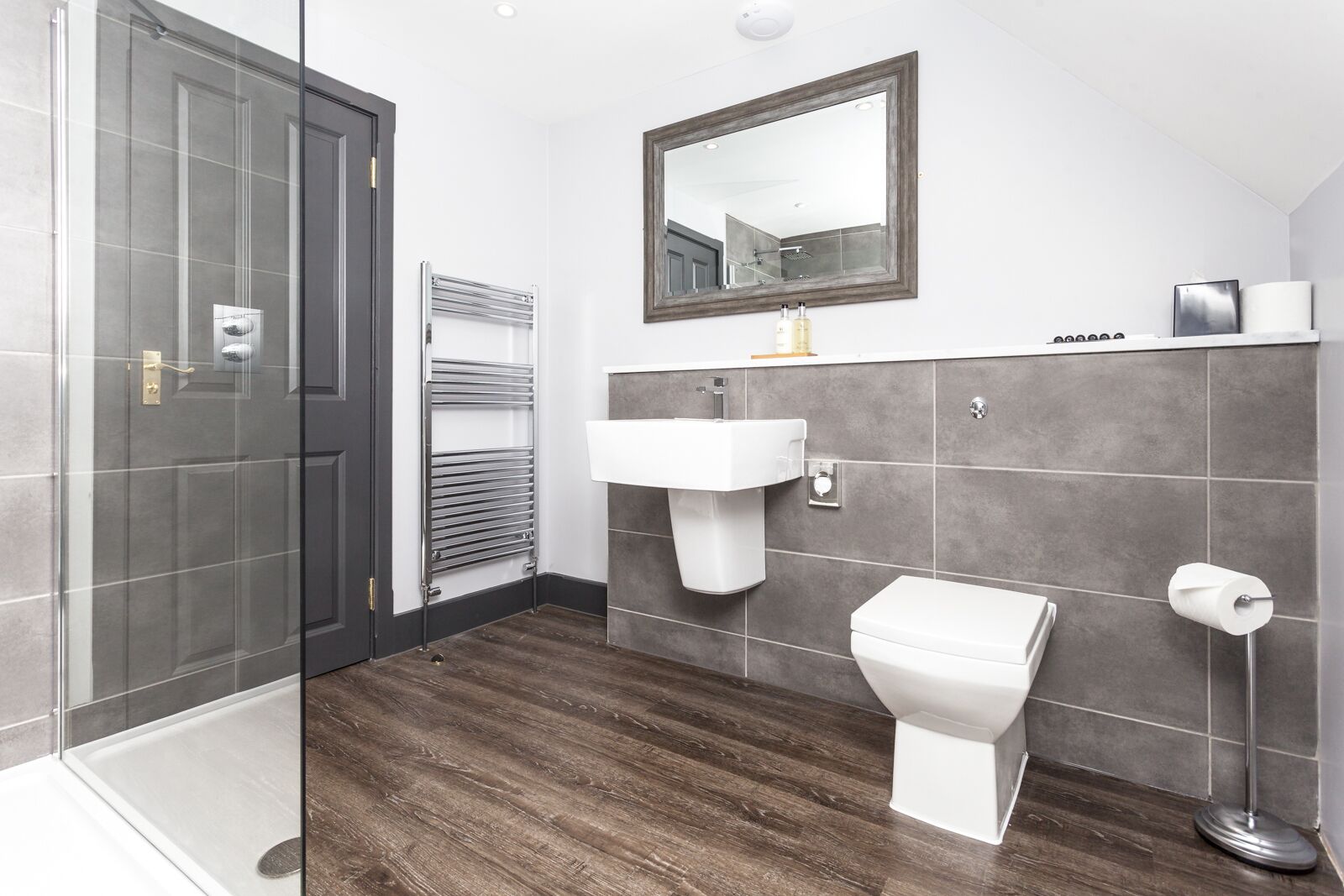 A modern bathroom with a glass shower enclosure, a white sink, and a toilet.