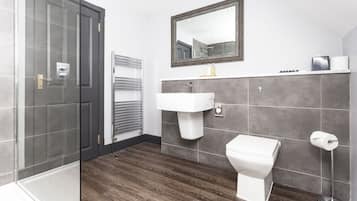 A modern bathroom with a glass shower enclosure, a white sink, and a toilet.