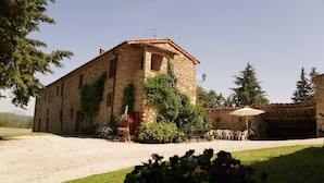 A rustic stone building with a garden in front, featuring a gravel path and outdoor seating. - Podere Le Rote Private Farmhouse (Castelnuovo di Val di Cecina)