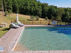A clear swimming pool with lounge chairs and a stone deck.